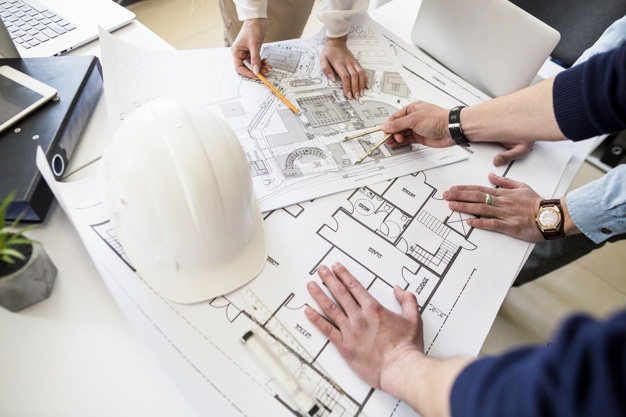 engenheiro-de-arquitetos-discutindo-na-mesa-com-planta_23-2147842977
