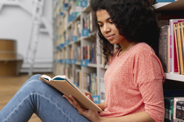 menina-de-baixo-angulo-na-biblioteca-na-leitura-do-chao_23-2148448006